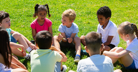 Group of elementary school children chatting on the green lawn