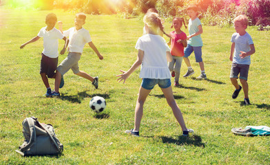 Obraz na płótnie Canvas Company of glad children playing football on the playground in park