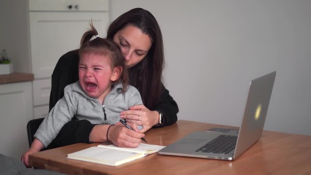 Stressed young woman working from home with small child. Home office of single mother