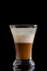 B52 coffee creamy alcohol cocktail in three layers in a shot glass on a black background