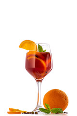 sangria or mulled wine cocktail in a glass with oranges, wine and juice on a white background
