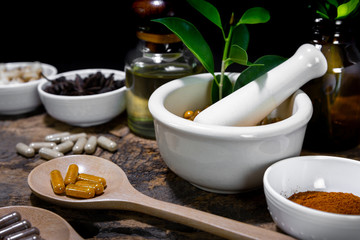 Herbal supplement in capsules on wooden spoon with healthy medicinal plant.Alternative drug or natural pharmaceutical capsule.Medication of vitamin supplemental for care and treatment.