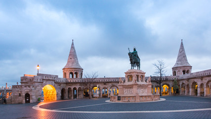 Fototapeta premium Catholic Matthias Church and Statue of Saint Stephen on Fishermans Bastion in Budapest, Hungary on sunrise with light from lanterns