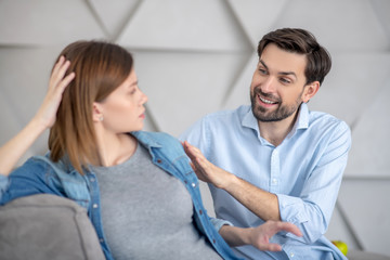 Fototapeta premium Young bearded man touching his wifes shoulder and smiling