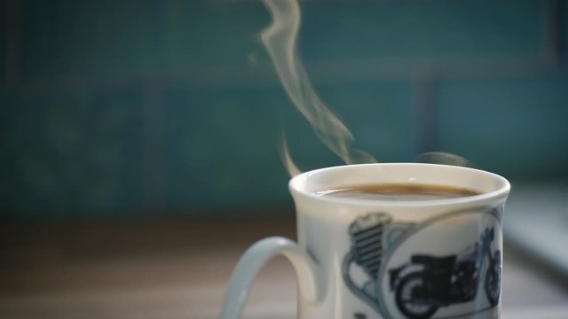Steaming coffee mug, close up, early morning at home in the kitchen