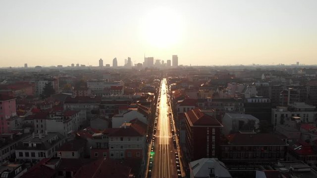 Drone aerial view of Milan skyline from above against bright sun over the city. Shot in Lambrate area during Coronavirus lockdown quarantine. Moving forward.