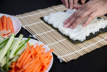 Chef preparing sushi roll over black table background - people with favorite dish Japanese food concept