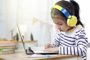 Asian schoolgirl learning at home with laptop computer using video call with her teacher, social distance during quarantine isolation during the Coronavirus (COVID-19) health care