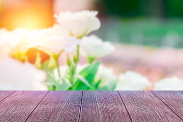 Empty vintage wooden table in font of blurry white rose in the garden and flare abstract background with copy space. Product display montage