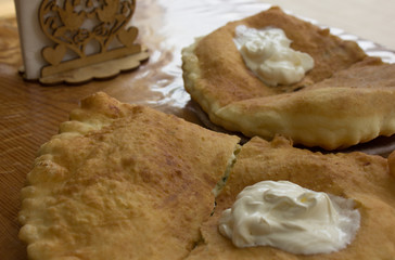 Fried pie with filling. Sour cream on a cheburek. Caucasian kitchen.