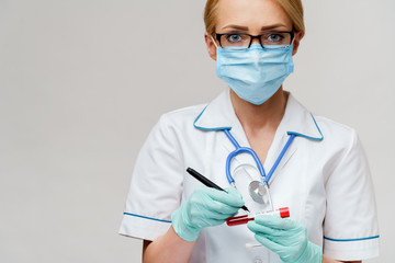 medical doctor nurse woman wearing protective mask and gloves - making mark by pen on virus blood test tube