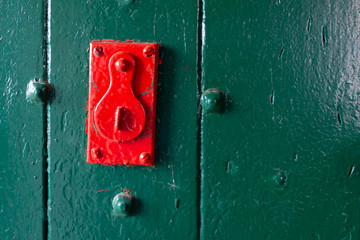 Red lock on green door. Maybe an old lock in a jail door. Danger lock