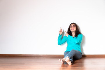 Brunette woman in blue shirt pointing finger to side in side position on isolated white background