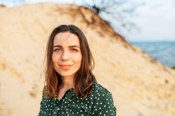 A young attractive woman in a green polka dress outdoors. A beautiful woman is walking on wild seashore © Vadim Pastuh
