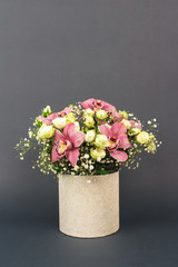 Vase with beautiful bouquet of orchids, roses and gypsophila, Baby's-breath flowers, on dark grey background with copy space for your text. Selective focus, celebrating concept