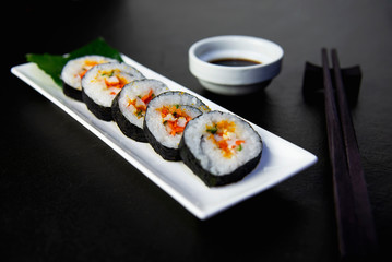Sushi roll set serving on white plate over black table background - favorite dish Japanese food concept