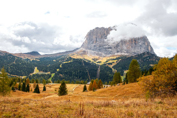 Typical hilly mountain landscape in Dolomites mountains with beautiful autumn colors in the background of the Sassolungo mountains