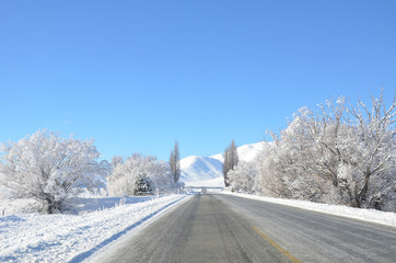 The winter snowy road from Lake Tekapo to Christchurch. The journey pass through several towns and along farmland, then the scenery will start to become mountainous.