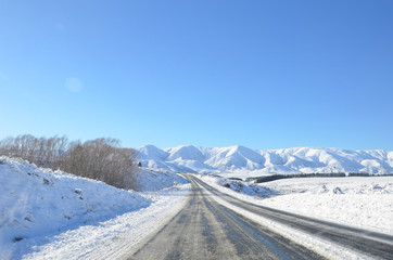 The winter snowy road from Lake Tekapo to Christchurch. The journey pass through several towns and along farmland, then the scenery will start to become mountainous.