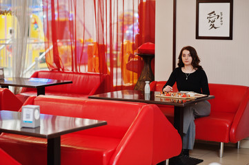 A young beautiful girl eating sushi on traditional Japanese restaurant.