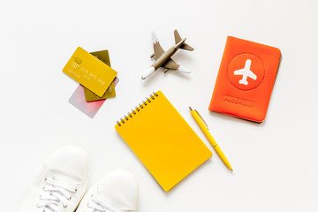 Outfit of traveler. Passport, shoes, notebook on white desk top-down