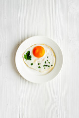 Fried eggs on plate - white wooden kitchen table top-down