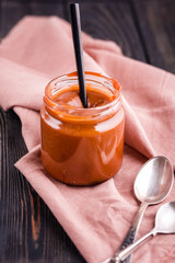 Homemade salted caramel in a glass jar with different spoons.