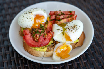 Two tasty sandwiches with boiled egg, green avocado and red tomato on plate, close up