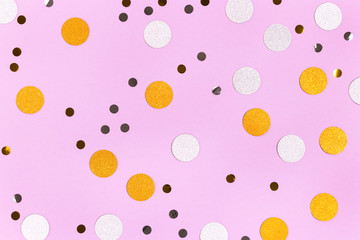 Golden and silver confetti scattered on a purple pastel background. Festive concept.