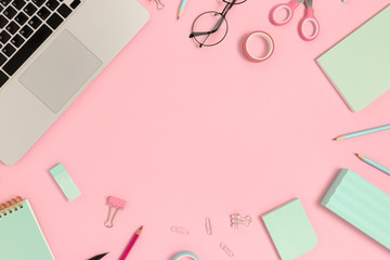 Frame made of laptop, glasses and stationery on a pink pastel background. Workspace concept with copy space.