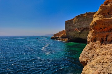 Fototapeta na wymiar View from Algar Seco Cave in Carvoeiro. Colorful cliffs beautiful turquoise Atlantic ocean with little boats in the distance in Algarve.