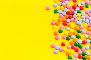 Color candy on yellow background top view frame copy space