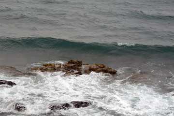 small waves at the stormy sea, with stones