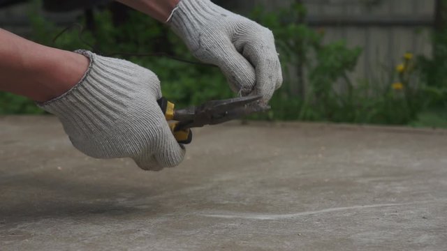 A man bites off a wire with pliers. Hands in close up.