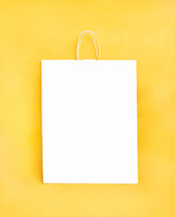 White paper package in the centre on a yellow background. Space for text