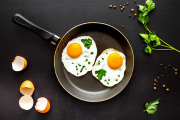 Fried eggs on frying pan on black desk top-down
