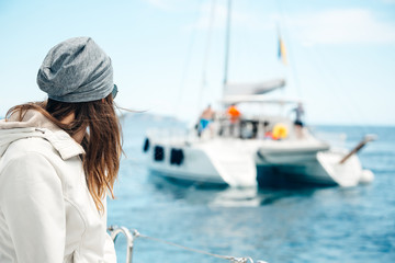 girl looks at the yacht sailing away into the distance, catamaran