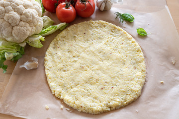 Vegetable pizza base from shredded cauliflower and cheese on baking paper, healthy alternative for...