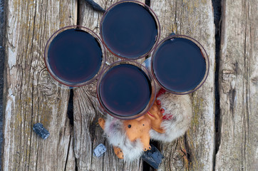 glasses of red wine and a figurine of an imp on wooden planks in the garden