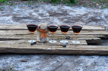 glasses of red wine and a figurine of an imp on wooden planks in the garden