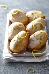 Madeleine cookies with lemon zest in a plate on a gray background.