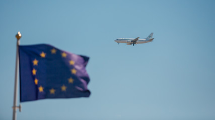 european union flag, flying airplane in the sky against the background of the flag of the European Union, flying under quarantine conditions, pandemics around the world, air carriers in quarantine - obrazy, fototapety, plakaty