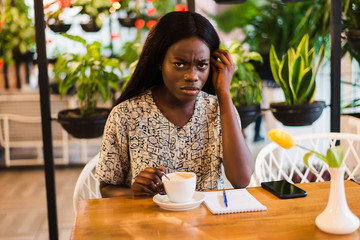 Young african woman drinking coffee in modern cafe