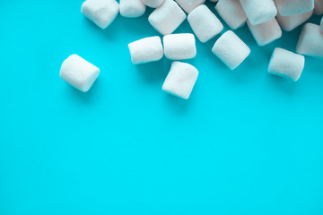 A few white little marshmallows scattered over a blue background
