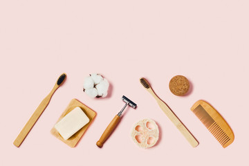 Zero waste accessories on pink background. Bathroom accessories on pink background. Natural bamboo toothbrushes, sponges, cotton flowers, shaving brush, razor. Flat lay, top view.