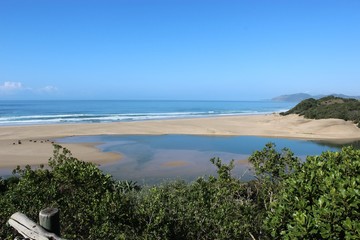 View over a river during low tide flowing out into the Indian ocean