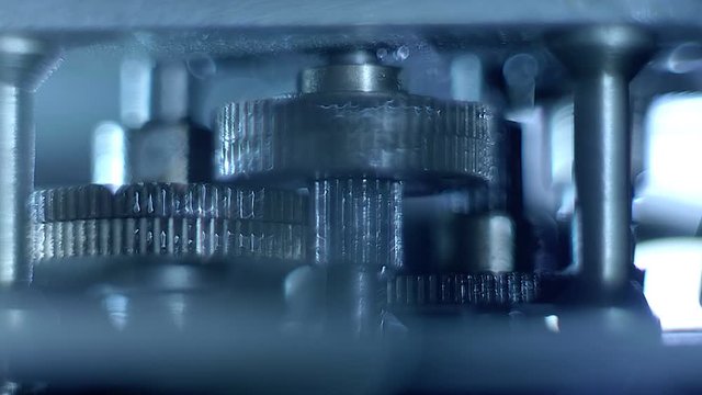 The metal gears in the lubricant rotate in the reduction mechanism to increase the force. Macro. Closeup. Shallow depth of field