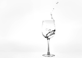 Water in a wine glass. Splash of liquid on a white background. Isolated object. Spray. Copy space for text. Selective focus.