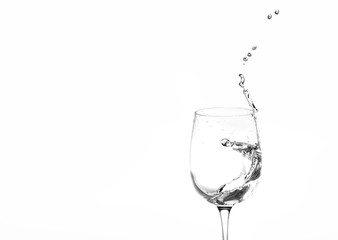 Water in a wine glass. Splash of liquid on a white background. Isolated object. Spray. Copy space for text. Selective focus.
