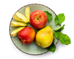 Red-yellow apples and pears with leaves on a green ceramic plate. Isolate on white background